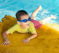 petit garçon sur tapis flottant de piscine